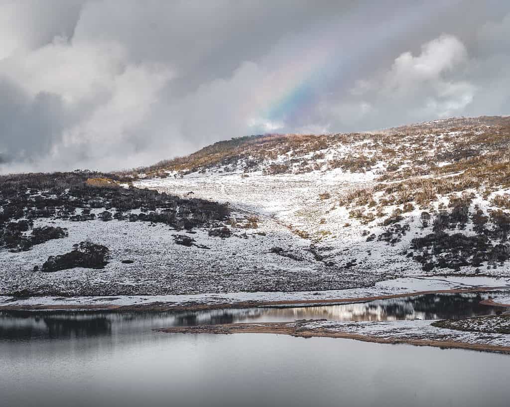 Falls Creek Lake in winter with grey skies and rainbow