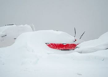 Falls Creek red car covered in snow with only door partially visible
