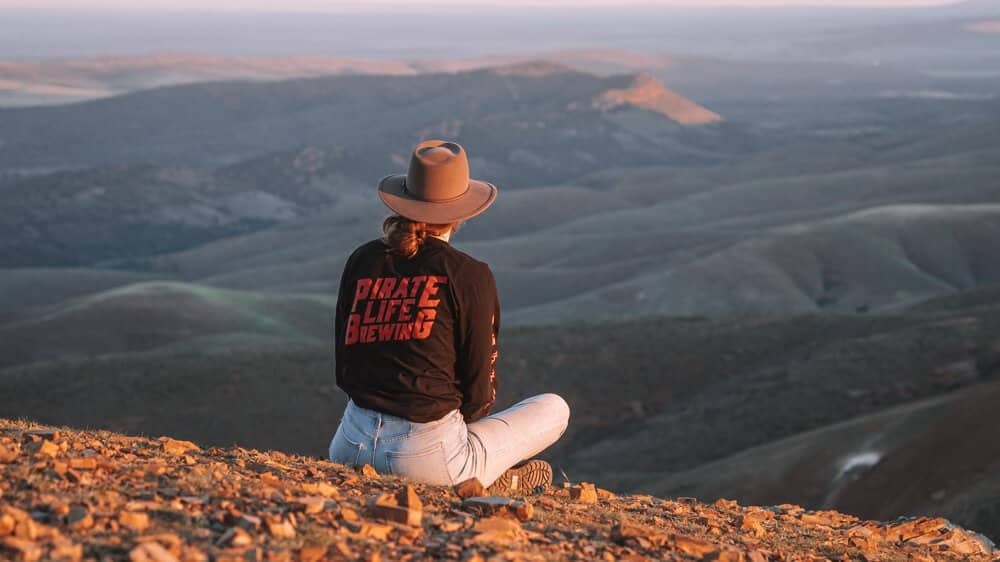 Female sitting down with view of mountains at sunset in the Flinders Ranges - South Australia Travel 