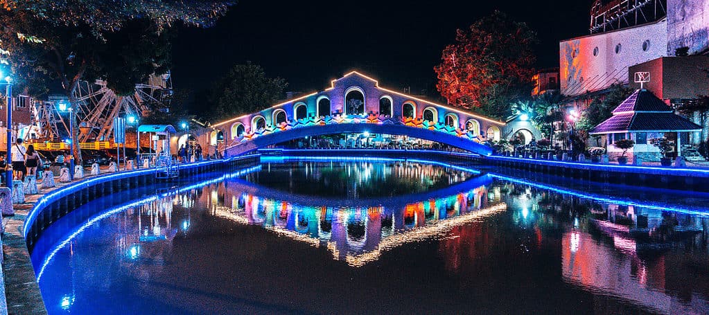 things to do in melaka -melaka river at night with bridge over river and colourful lights