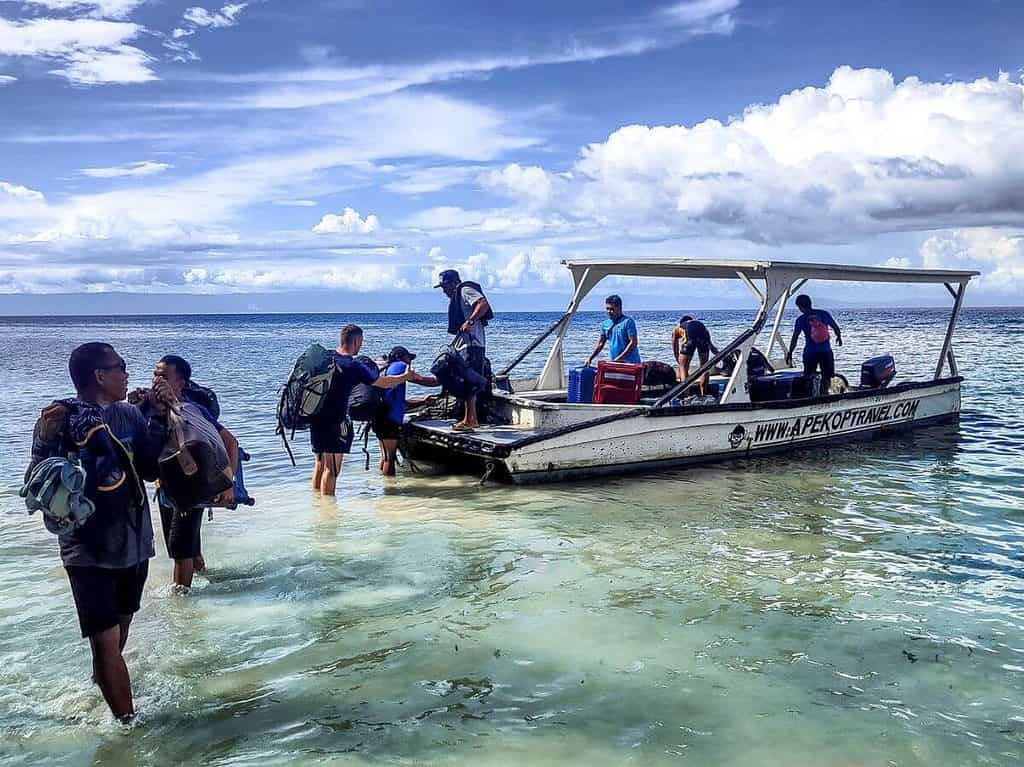 People carrying luggage from small boat to Momo Beach